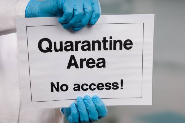 Doktorun elinde tıbbi eldiven var. Yasak bölgenin önünde karantina işareti var.