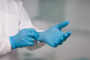 Tıbbî eldivenleri bir kliniğin önünde tak.