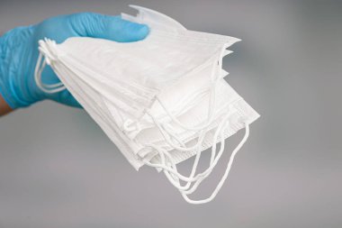 Doktorun elini tıbbî eldivenlerle kapattığımızda enfeksiyona karşı korunmak için tıbbi maske seti görülüyor.