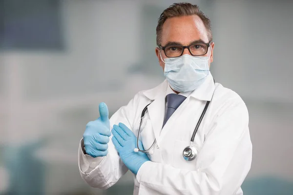 doctor with medical face mask and medical gloves shows thumbs up