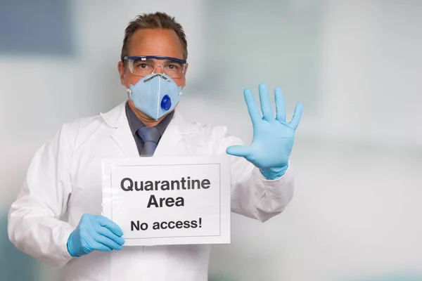 Doctor with medical face mask and medical gloves showing quarantine sign in front of a restricted area and is making stop gesture