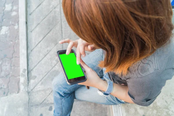 Hermosa chica sosteniendo un teléfono inteligente en las manos de un scre verde —  Fotos de Stock