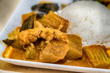 Körili tavuk ve pirinç beyaz bir plaka üzerinde.