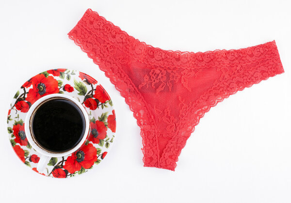 Red women's panties and a coffee cup on a white background