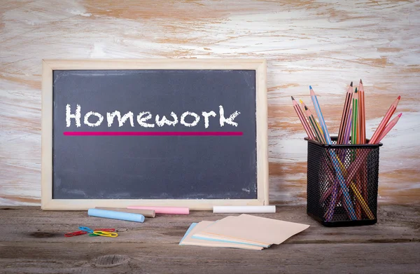 Homework text on a blackboard. Old wooden table with texture — Stock Photo, Image