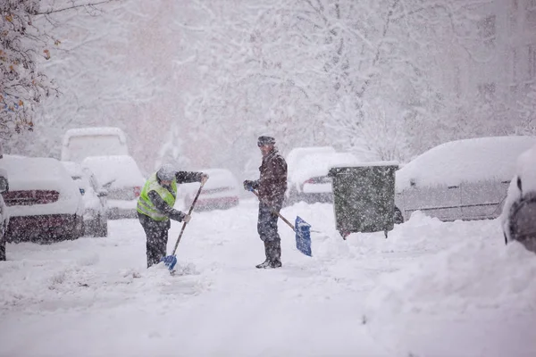 RIGA, LATVIA - NOVEMBRO 4: Homem limpando neve de uma passarela, sno — Fotografia de Stock