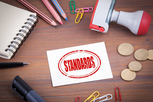 Standards stamp. Wooden office desk with stationery, money and a