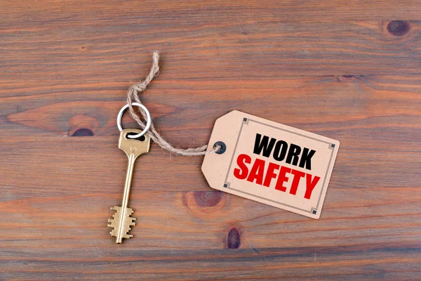 Ключ и записка на деревянном столе с текстом - Безопасность труда — стоковое фото