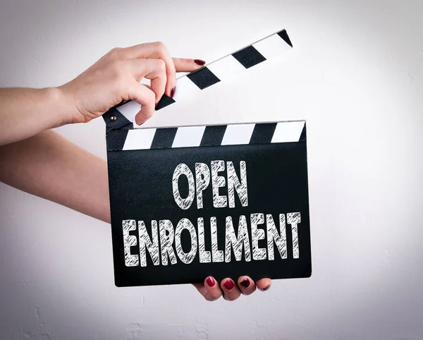 Open enrollment. Female hands holding movie clapper