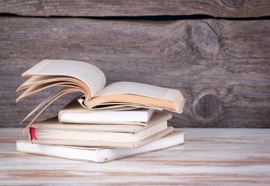 Tahta bir masada yığınla kitap.