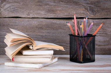 Kitaplar ve kalemler üzerinde ahşap masa yığını