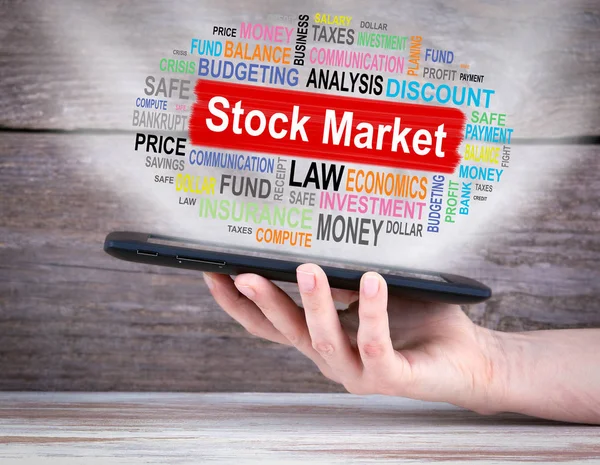 Stock Market Concept. Tablet PC in de hand. Oude houten achtergrond — Stockfoto