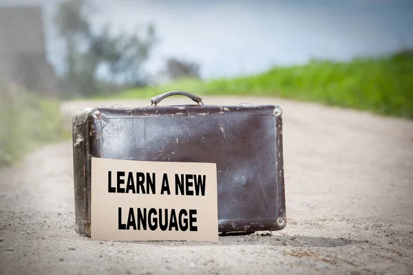 Вивчайте нову мову. Стара подорожня валіза на заміській дорозі — стокове фото