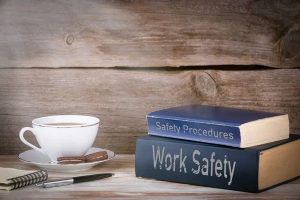 Procedimientos de seguridad y protección del trabajo. Montón de libros sobre escritorio de madera — Foto de Stock