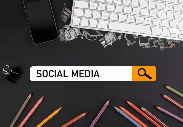 Concetto di social media. matite colorate e una tastiera per computer con un telefono cellulare su un tavolo nero — Foto Stock