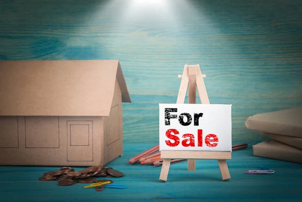 A la venta. modelo de casa, dinero y un tablón de anuncios bajo la luz del sol — Foto de Stock