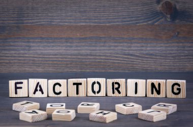 Ahşap blok üzerinde yazılı kelime Faktoring. Koyu ahşap arka plan doku ile