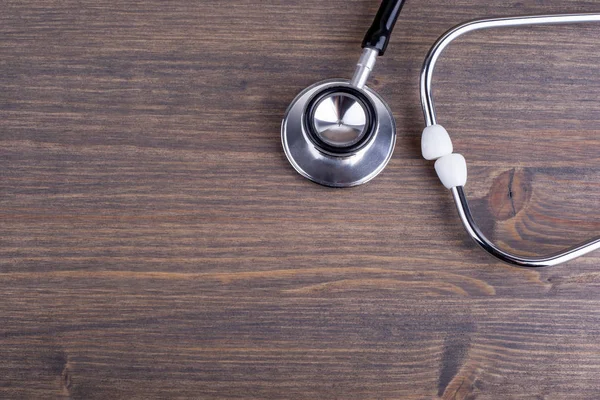 Lugar de trabajo de un médico. Estetoscopio sobre fondo escritorio de madera — Foto de Stock