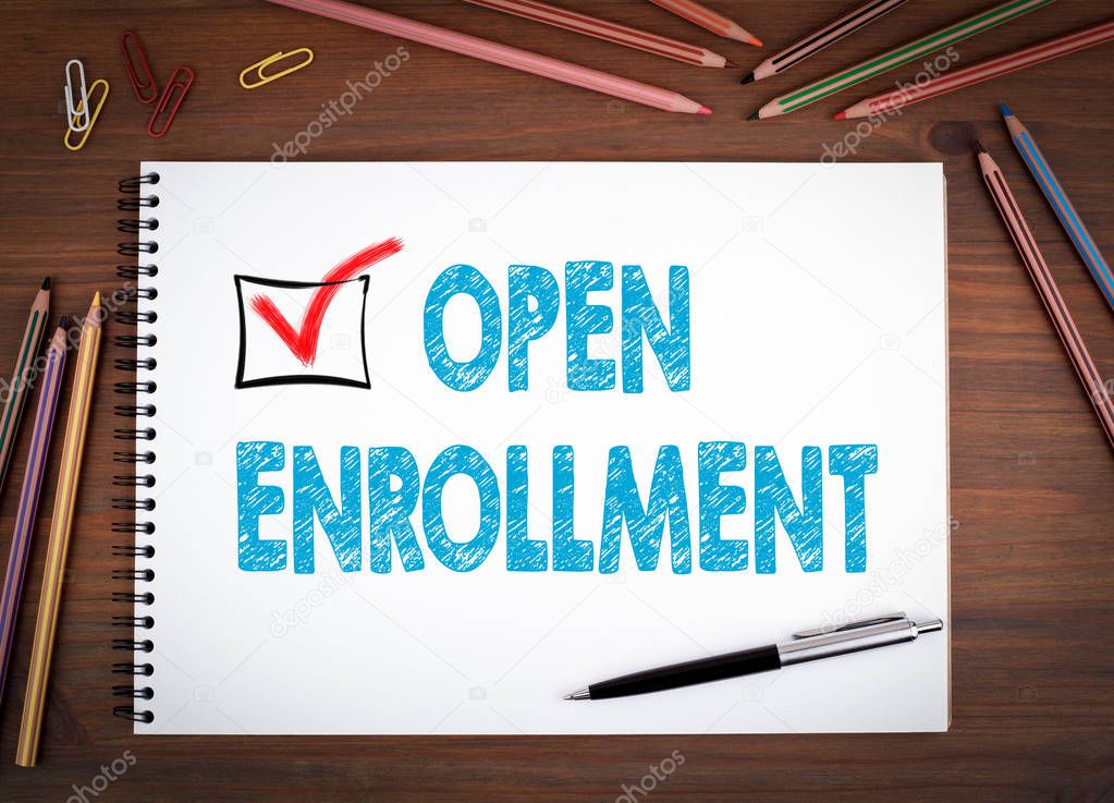 Open Enrollment. Notebooks, pen and colored pencils on a wooden table