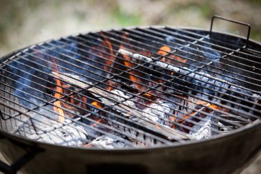 Barbekü Izgara yangın yakın çekim. İçinde belgili tanımlık geçmiş yeni ve eski yetişkin çimen