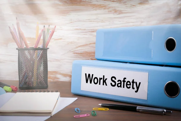 Seguridad en el trabajo, carpeta de oficina en escritorio de madera. En la mesa lápices de colores, lápiz, papel de cuaderno — Foto de Stock