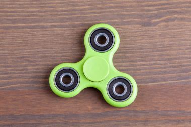 Yeşil topluca spinner stres giderici oyuncak ahşap arka plan üzerinde