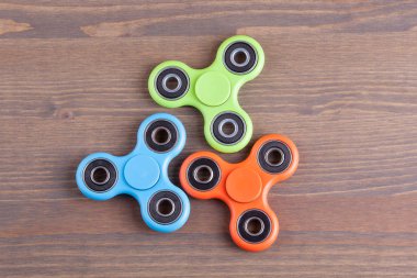 Turuncu, mavi ve yeşil spinner stres giderici oyuncak ahşap arka plan üzerinde kıpır