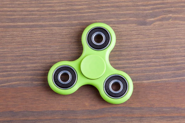 Yeşil topluca spinner stres giderici oyuncak ahşap arka plan üzerinde