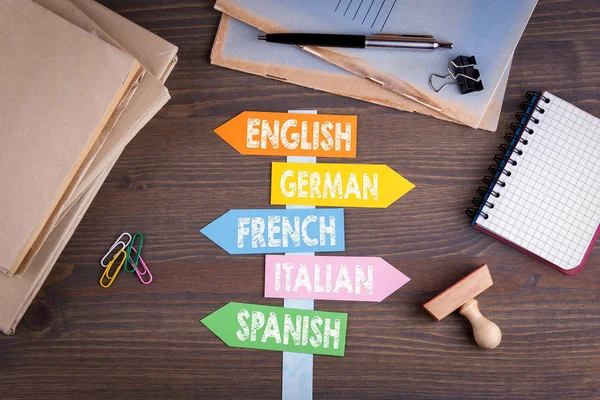 Languages concept. Paper signpost on a wooden desk — Stock Photo, Image