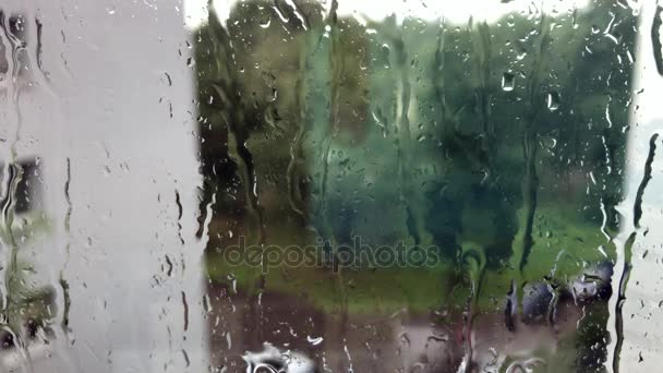 Drops of rain on the glass window, buildings in background — Stock Video