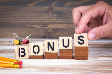 Bonus kavramı. Ahşap mektup ofis masasında bilgilendirici ve iletişim arka plan