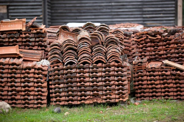 Old clay tile roof tiles stacked on wooden pallets. The background for construction restoration and logistics — Stock Photo, Image