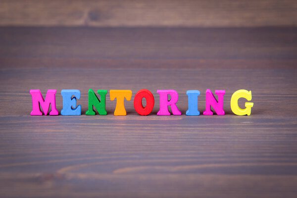 Mentoring. colored wooden letters on a dark background.