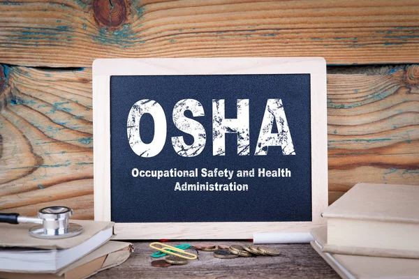 Osha, Ufficio per la sicurezza e la salute sul lavoro. Lavagna su fondo di legno — Foto Stock