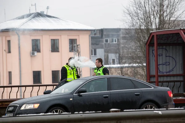 Latvia, Riga - December 1.2017: Municipal police of Riga, Latvia at the place of accident by the car. Smoking electronic cigartes — Stock Photo, Image