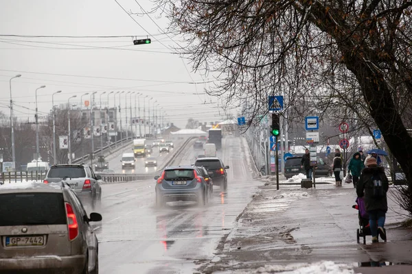 Lettland, Riga - 1. Dezember 2017: nasser Schnee in der Stadt, Verkehr und Menschen auf den glatten Straßen — Stockfoto