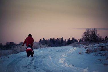 erkek ve çocuk walikng ülke yolda ve donma ve soğuk kış çekerek kızak