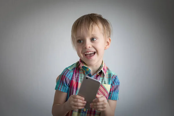 Niño pequeño con un teléfono inteligente en sus manos. retrato de niños — Foto de Stock