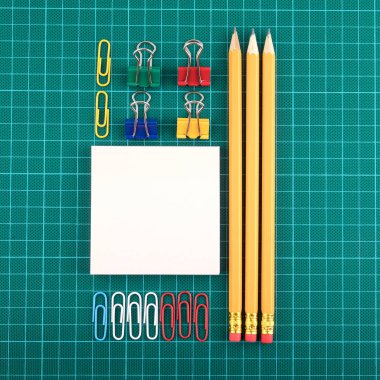 Ataç, kalemler ve not sayfasını kontrol yeşil artalan üzerinde