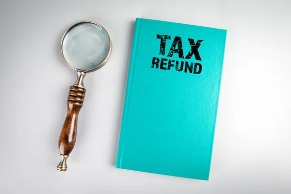 Reembolso de impostos. Capa de livro verde e lupa — Fotografia de Stock