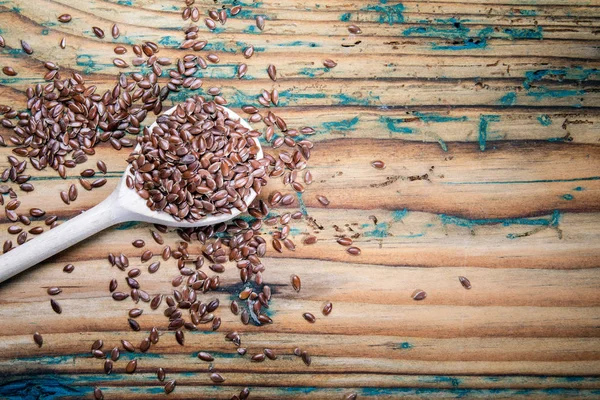 Leinsamen und ein Löffel auf einem alten Holztisch — Stockfoto