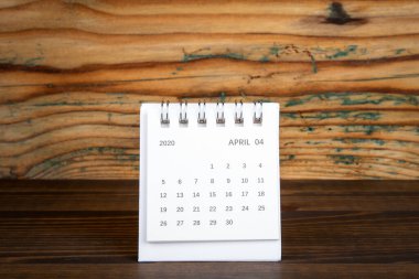 2020 April. White paper calendar on a wooden table. Time planning