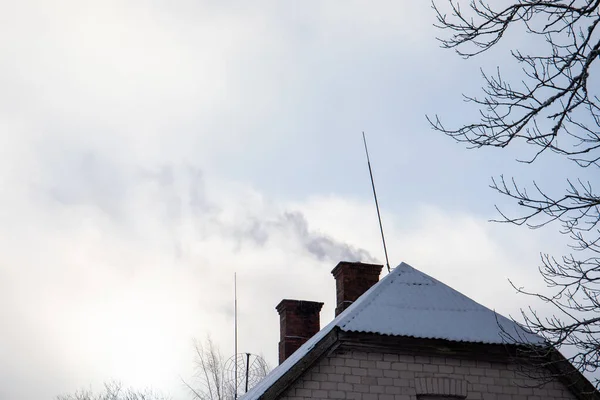 Dunkler Rauch quillt aus dem Kamin eines Hauses, Wintertag — Stockfoto