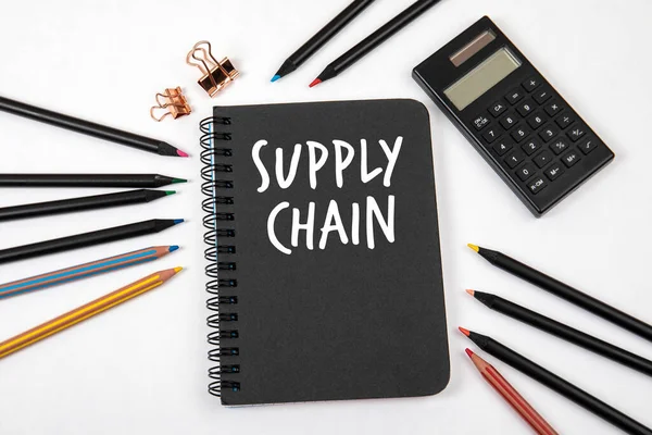 SUPPLY CHAIN concept. Black notebook and office supplies
