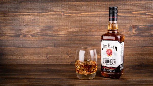 Bir şişe Jim Beam Bourbon ve ahşap arka planda buzlu bir bardak. — Stok fotoğraf