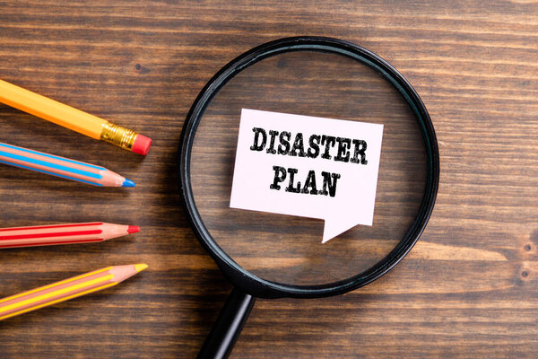Концепция DISASTER PLAN. Черное увеличительное стекло, речевой пузырь и цветные карандаши
