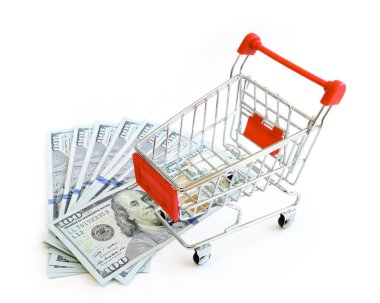 Stüdyo 100 dolarlık banknot yığını ve beyaz üzerine izole edilmiş küçük alışveriş arabası.
