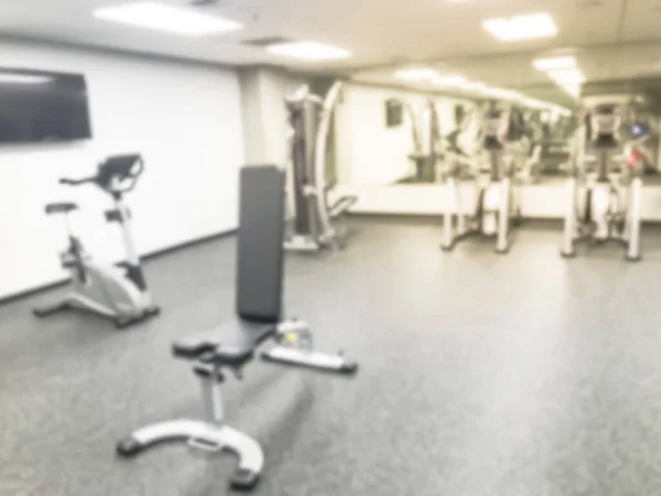 Suddig bakgrund löpband, elliptisk, strider och träningsutrustning på modernt gym i Usa — Stockfoto