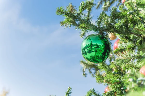 Adorno de bola verde colgando en las ramas de pino de Navidad en el primer plano de luz diurna — Foto de Stock