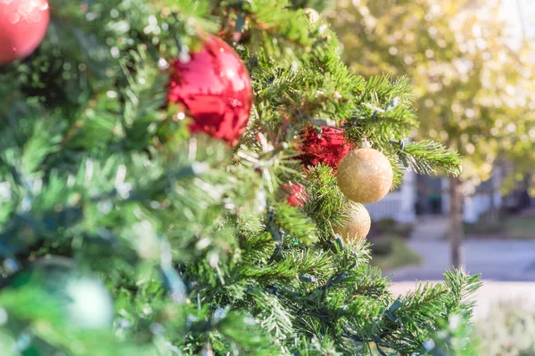Bola de Navidad de cerca en ramas de pino con casa residencial de dos pisos en el fondo — Foto de Stock